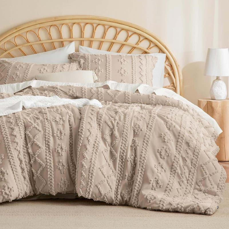 A queen-size comforter set in beige with embroidered tufts and a Boho design, displayed on a bed with white and beige pillows.