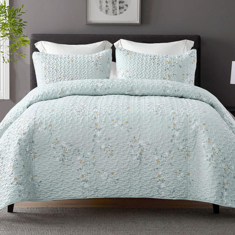 Light blue quilt with floral pattern on a bed in a bedroom setting